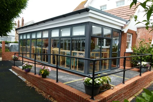 The bright glass conservatory dining room at Ashdown Nursing Home